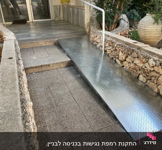 רמפה מתכתית ליד מדרגות בכניסה לבניין